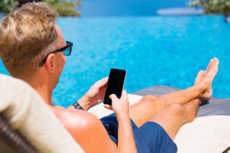 Man using smartphone by the pool.の写真素材