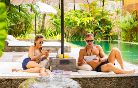 Couple busy with tech gadgets while on vacationの写真素材