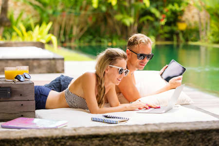 Woman and man using computers by the poolの写真素材