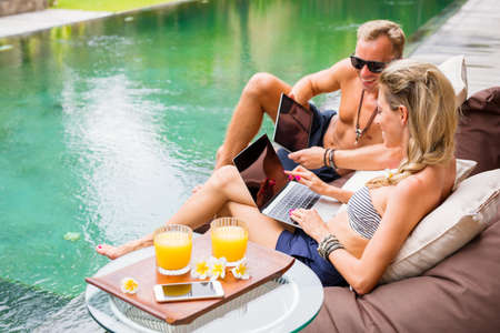 Couple working by the poolの写真素材
