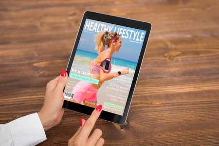 Woman reading healthy lifestyle magazine on tabletの写真素材