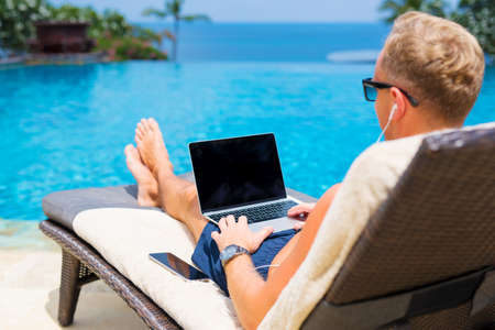 Man working with laptop by the poolの写真素材