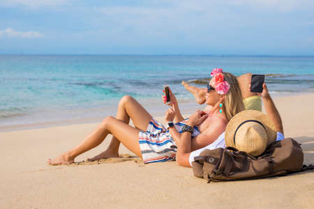 Couple on the beach with mobile phonesの写真素材