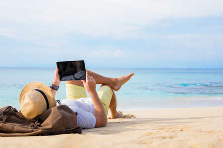 Man with tablet on the beachの写真素材