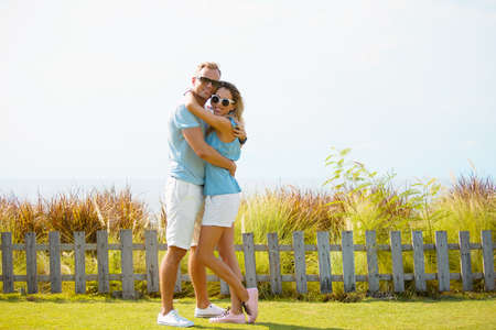 Full length couple embracing and looking at cameraの写真素材