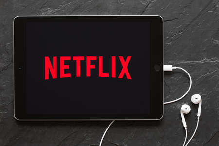 Riga, Latvia - March 25, 2018: Earphones connected to iPad showing Netflix logo on the screen.のeditorial素材