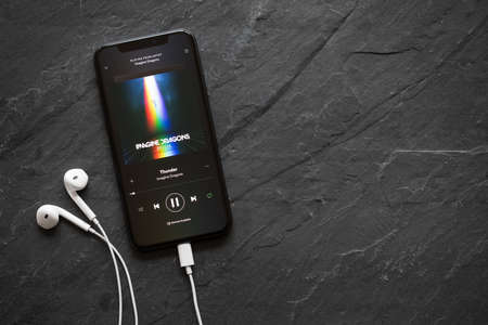 Riga, Latvia - March 25, 2018: iPhone X playing song Thunder by Imagine Dragons on Spotify app.のeditorial素材