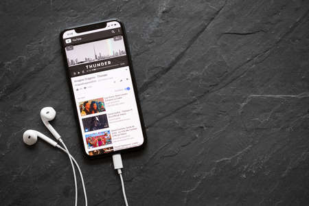 Riga, Latvia - March 25, 2018: iPhone X playing song Thunder by Imagine Dragons on YouTube video player.のeditorial素材