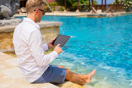 Man using tablet by the poolの写真素材