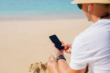 Young man using mobile phone on the beachの写真素材