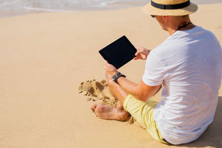 Young man using tablet on the beachの写真素材