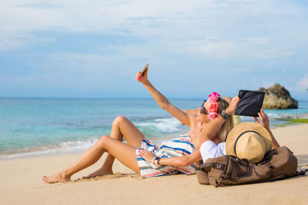 Couple relaxing on the beach and using tech devicesの写真素材