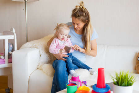 Mom and baby playing with mobile phone togetherの写真素材