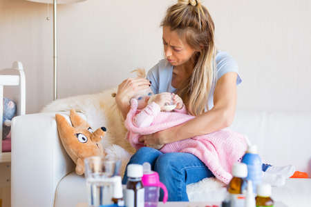 Mom with sick baby at homeの写真素材