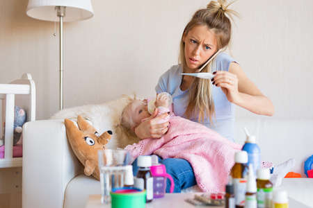 Woman with sick baby calling doctorの写真素材