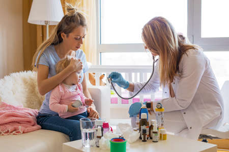 Doctor visit sick baby at homeの写真素材