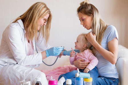 Pediatrician doctor visiting baby at homeの写真素材