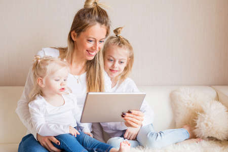 Mother using tablet together with her daughtersの写真素材