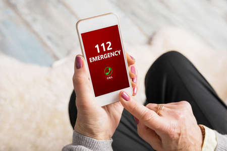 Old woman dialing emergency number 112 on phoneの写真素材