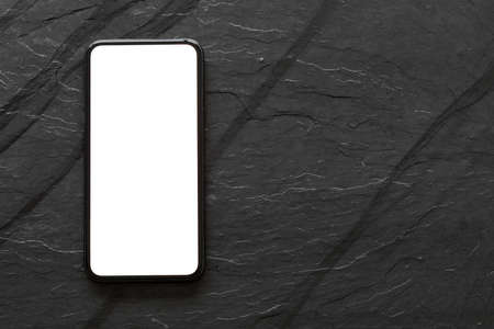 Mobile phone with empty screen on black stone surfaceの写真素材