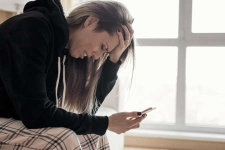 Woman holding phone and cryingの写真素材