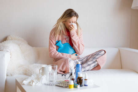 Sick woman sitting in sofaの写真素材