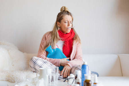 Sick woman measuring temperature with thermometer in her mouthの写真素材