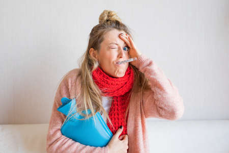 Funny picture of sick woman measuring temperature with thermometer in her mouthの写真素材
