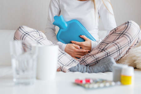 Woman with hot water bottle healing stomach painの写真素材