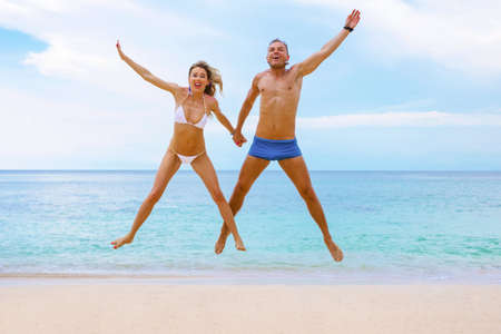 Excited couple jumping on the beachの写真素材
