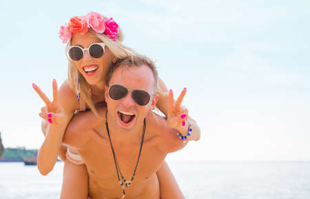 Boyfriend piggybacking his girlfriend on the beachの写真素材