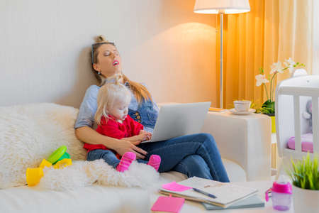 Exhausted mother fallen asleep in front of computerの写真素材