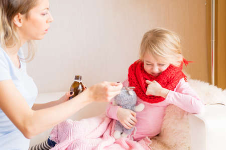Mom giving medicines to her sick childの写真素材