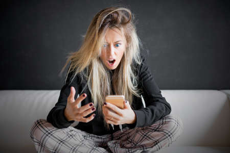 Frustrated woman looking at her phoneの写真素材
