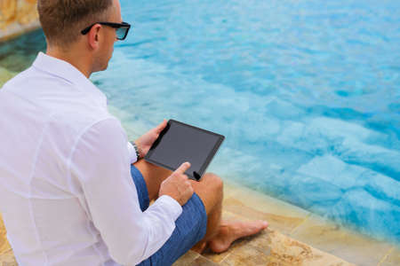 Business man using tablet by the poolの写真素材