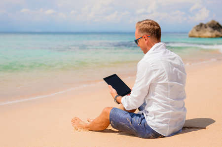 Businessman with tablet on the beachの写真素材