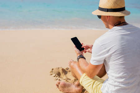 Man with phone on the beachの写真素材