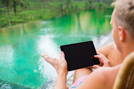 Man holding tablet in tropical villa by the poolの写真素材