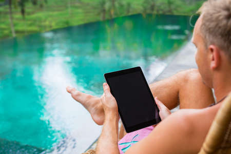 Man using tablet by the poolの写真素材