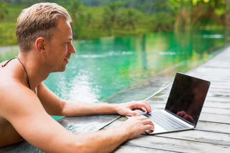 Man with laptop by the poolの写真素材