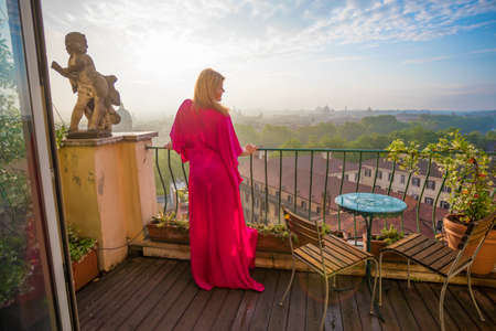 Woman standing on balcony in morningの写真素材