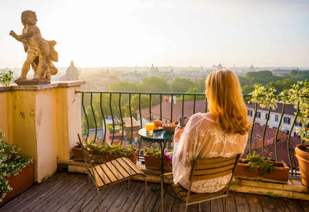 Woman sitting on balcony in early morningの写真素材