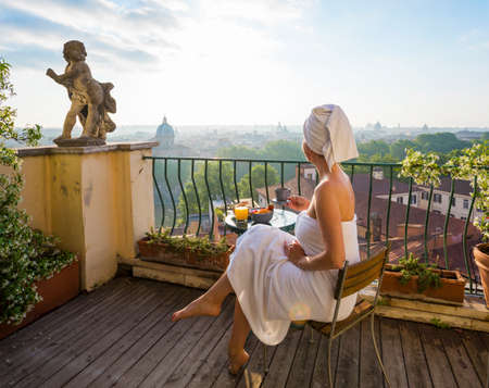 Woman having breakfast on balcony in cityの写真素材