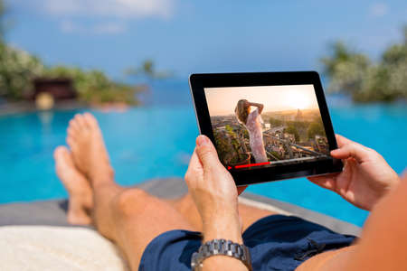 Man watching movie on tablet by the pool.の写真素材