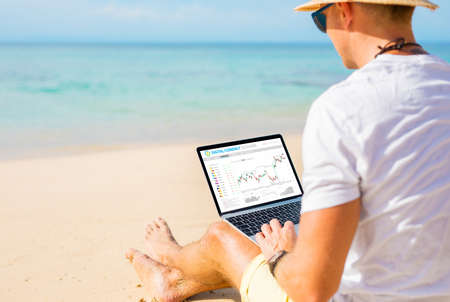 Man trading cryptocurrencies on the beach.の写真素材