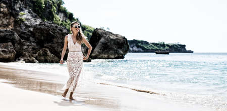 Woman walking by the beach. High contrast photo filter effect.の写真素材