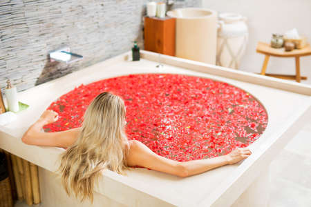 Woman in bathtub with red flowersの写真素材