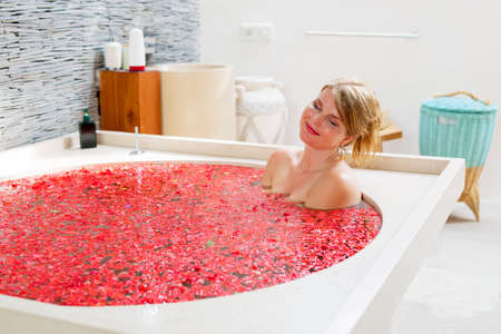 Woman relaxing in red flower bathの写真素材