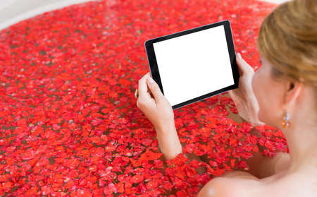 Woman holding tablet with blank screen in bath, moskup for you own designの写真素材