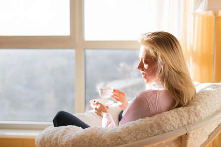 Woman drinking tea while relaxing at homeの写真素材
